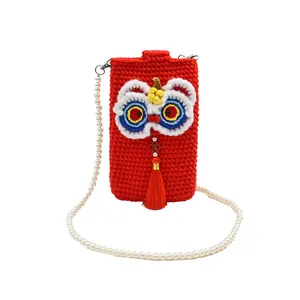 Macro detail of red crochet lion dance phone bag with pearl strap and tassel decoration