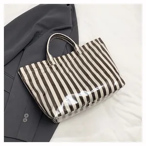 Détail du sac cabas à rayures avec revêtement brillant sur fond de blazer gris