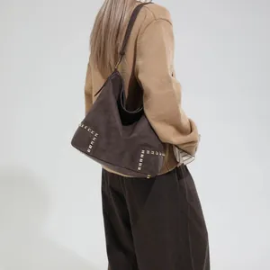Large vintage brown faux suede hobo bag with gold rivet studs and shoulder strap on model