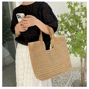 Close-up of woven straw tote bag with brown leather handles and natural fiber texture