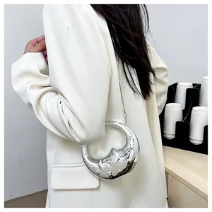 Detail of silver crescent moon shoulder bag with liquid metal finish and chain strap