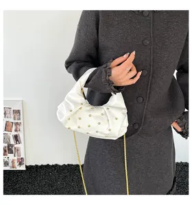 Detail of white pleated handbag with gold rivets and metallic chain strap on shoulder
