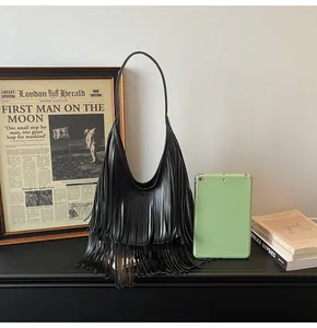 Dettaglio di borsa hobo in pelle nera con frange e tracolla in un ambiente vintage