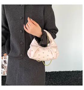 Pink pleated crescent bag with sparkling rhinestones and a gold chain strap on a model