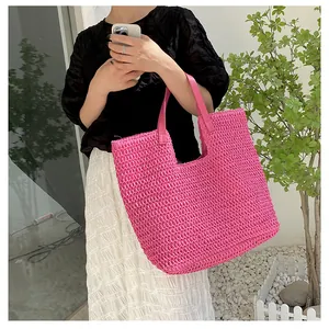 Detail of rose pink woven tote bag with leather handles shown in outdoor setting