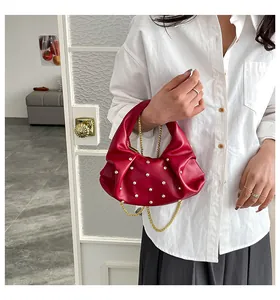 Detail of red crescent bag with sparkling studs and elegant golden chain strap