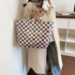 Brown checkerboard tote bag with TOTE BAG text shown being held by a fashion model