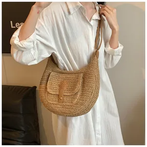 Detailed macro view of woven straw texture and brown leather strap on hobo shoulder bag