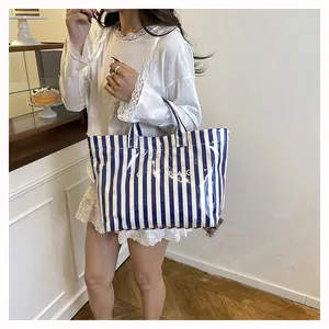 Détail du sac cabas à rayures bleues et blanches avec couche PVC tenu par un modèle