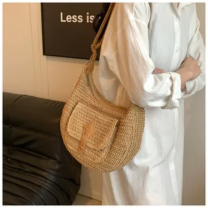 Detail of woven straw shoulder bag featuring a front pocket and adjustable leather strap