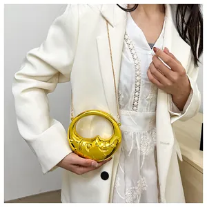 Detail of creative gold moon-shaped crossbody bag with unique face relief and metal chain