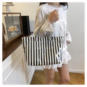 Gros plan d'un sac cabas rayé noir et blanc brillant porté par un mannequin en café