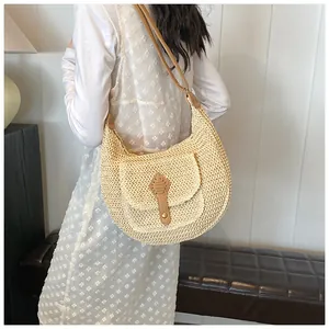 Detail of straw woven shoulder bag with brown leather strap and front flap pocket