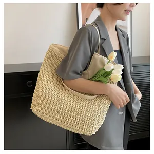 Detail of a large woven straw tote bag in cream with smooth shoulder straps and soft texture