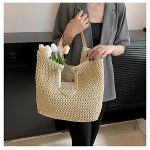 Close-up of beige straw tote bag with cream leather handles and hollow knit texture