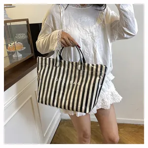 Détail d'un sac cabas à rayures avec finition brillante et lettrage blanc TOTE BAG