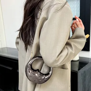 Metallic crescent moon bag with star embossing and gold chain strap on grey blazer
