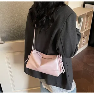 Detail of light pink shoulder bag featuring decorative side ribbons and metallic zipper