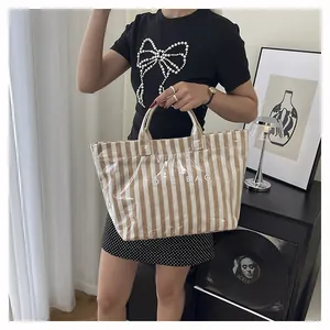 Détail d'un sac cabas à rayures avec revêtement transparent imperméable et texte TOTE BAG