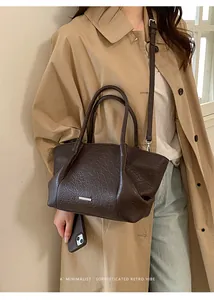 Détail de la texture cuir plissé rétro et du logo en métal sur le cabas marron