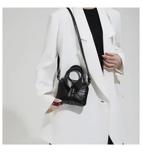 Detailed close-up of a creative black mini jacket-shaped leather bag on a white suit