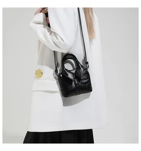 Detail of creative black shirt-shaped leather crossbody bag with collar and button design