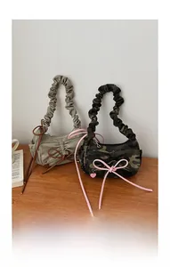 Detail view of canvas baguette bags with ruffles, bows, and heart pendants on wood