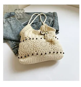 Detail view of a bohemian hand-crocheted tote bag with fringe tassels and bead accents