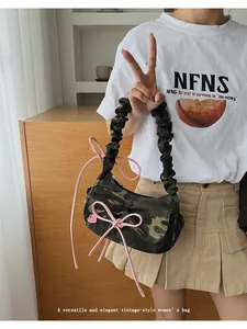 Detail of camouflage crescent bag with pink bow accents and ruched shoulder strap