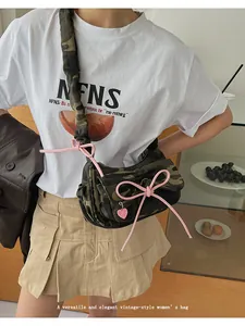Detail of camouflage crescent bag featuring pink ribbon bows and a heart pendant