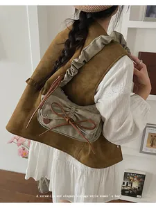 Close-up of khaki pleated baguette bag with bow detail on a stylish autumn outfit