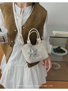 Detail of cream vintage-style handbag with star pendant and sleek metallic hardware