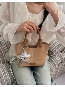 Detail of retro khaki handbag featuring unique knot rings and star charm on PU leather