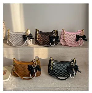 Five elegant hobo bags in various colors with ribbon bows and pearl charms on steps