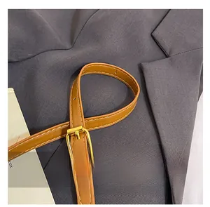 Detail of brown leather shoulder strap with gold buckle and fine stitching contrast