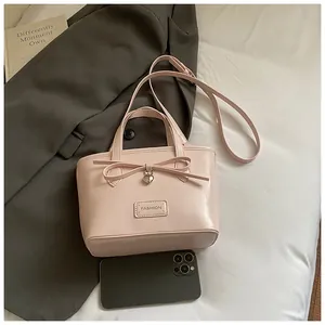 Detailed close-up of pink tote bag with bow accent, heart charm and adjustable strap