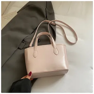 Detail of pink bow tote bag with dual handles and slim shoulder strap on grey blazer