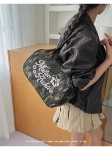 Detail showing vintage camouflage tote bag with Matau Archive text held by a model