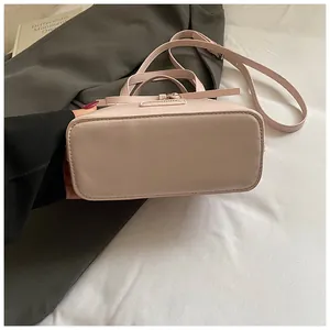 Detail view of pink tote bag bottom with fine stitching and fashion brand plaque