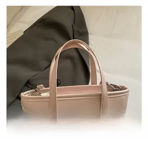 Close-up of pink leather tote bag featuring decorative bow and silver heart pendant detail