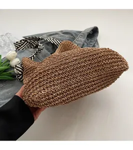 Detail of hand-woven brown straw tote bag with black and white striped handles
