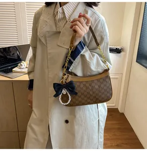 Brown underarm bag with M-pattern logo, gold chain strap, and pearl bow detail