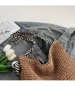 Detailed texture of straw tote bag with black and white striped fabric shoulder strap