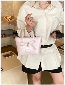 Close-up of pink tote bag featuring a bow, heart pendant, and Fashion label