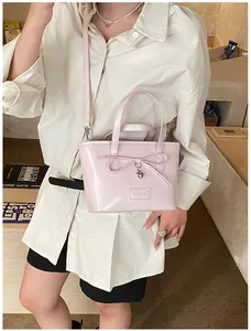 Close-up of pink patent leather tote bag with bow detail and heart pendant decoration