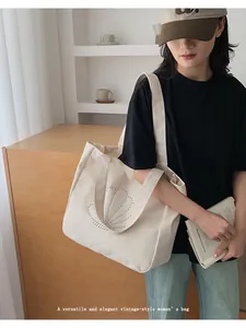 Detailed view of cream canvas tote bag featuring a sparkling shell motif and rivets