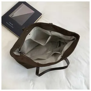Interior view of brown tote bag showing beige fabric lining with zipper pocket and compartments