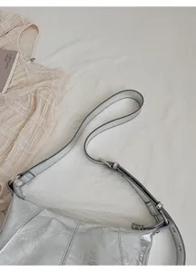 Detail of silver metallic textured crossbody bag with adjustable strap and zipper closure