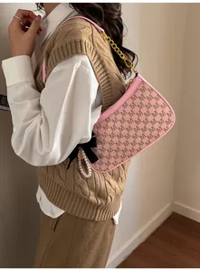 Detailed view of pink shoulder bag with letter prints, gold chain and black bow charm