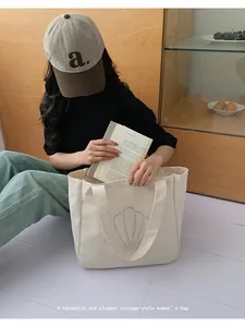 Detail of off-white canvas tote bag featuring metallic stud shell pattern and large space